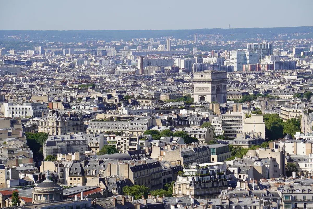 Aerial view of iconic Paris skyline showcasing the historic Arc de Triomphe amid urban cityscape.