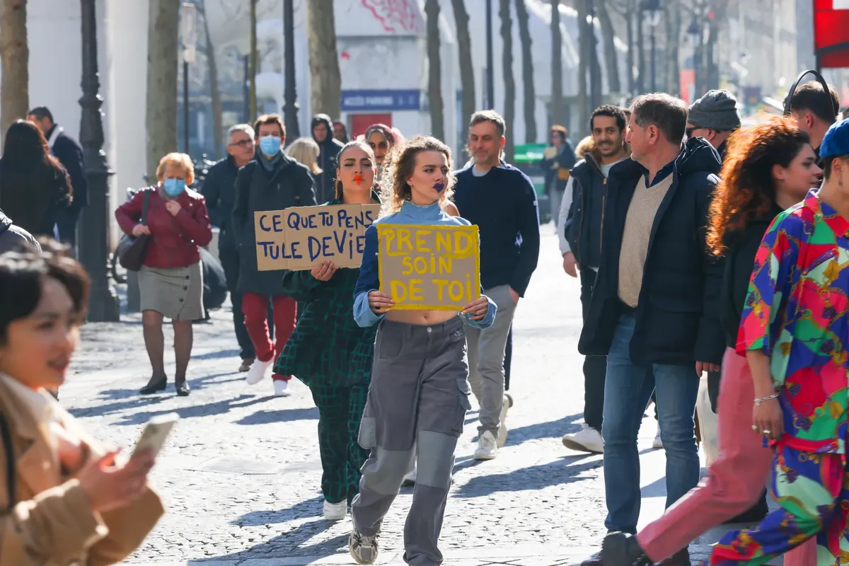 Women holding protest signs on a busy street advocating social issues.