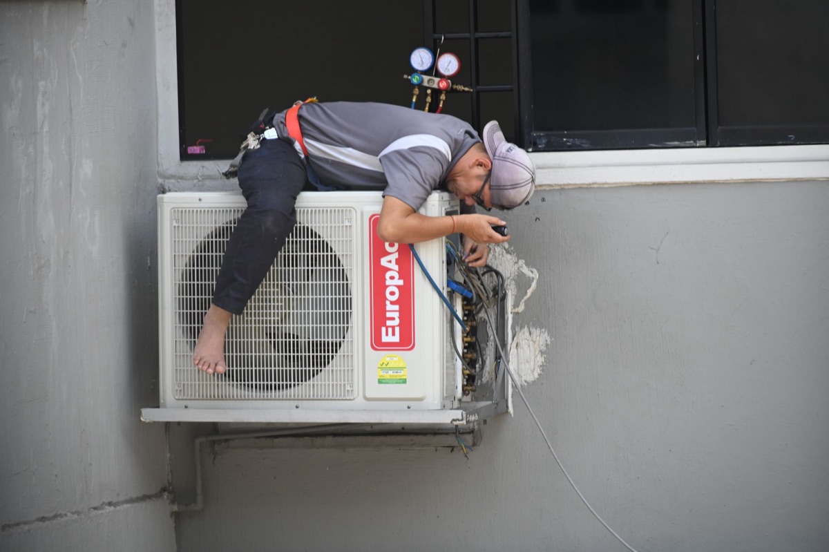 Air conditioner being installed in a Parisian apartment, showing the technical process and the context of the political debate