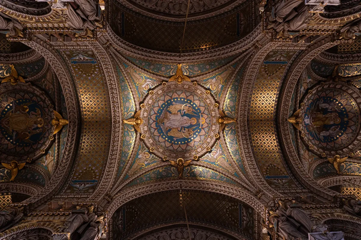 Intricate mosaic ceiling of Notre-Dame de Fourvière in Lyon, featuring religious art and detailed patterns.