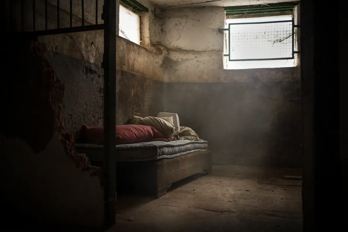 A haunting image of an abandoned room with a dusty bed and dim lighting accents.