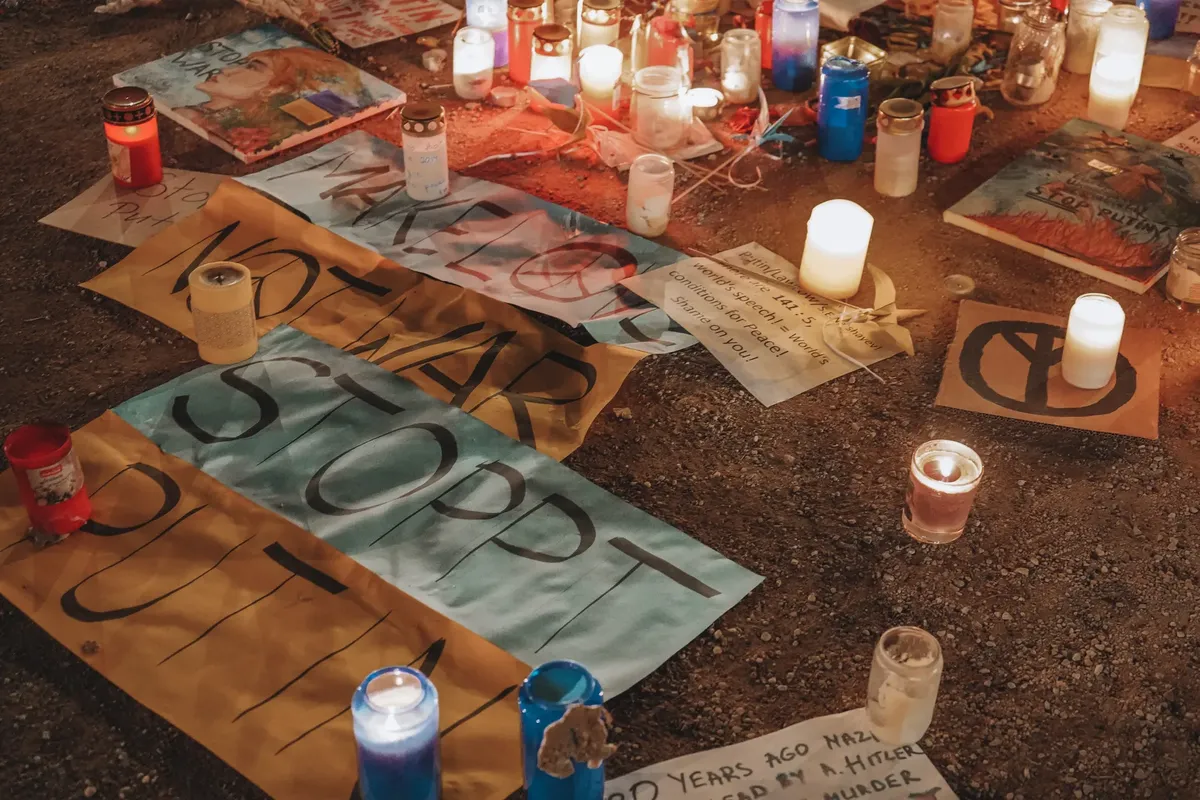 Vigil in Berlin with candles and protest signs against war, highlighting peace efforts.